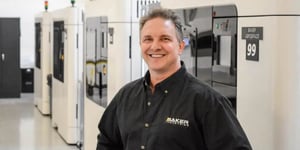 Jerry Kablak, Program Engineer at Baker Industries, a Lincoln Electric Company, standing in front of 3D printers