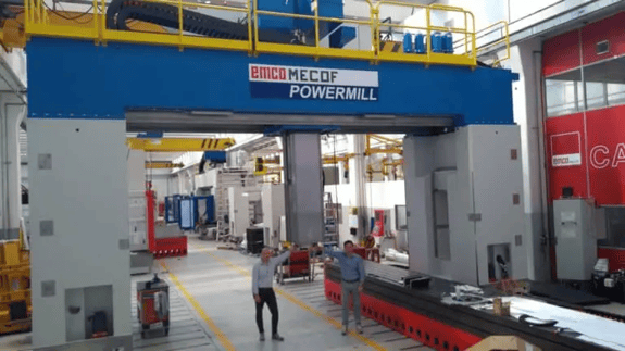 Image of two people standing under the Emco MECOF PowerMill, a massive 5-axis CNC machining center for large-scale machining